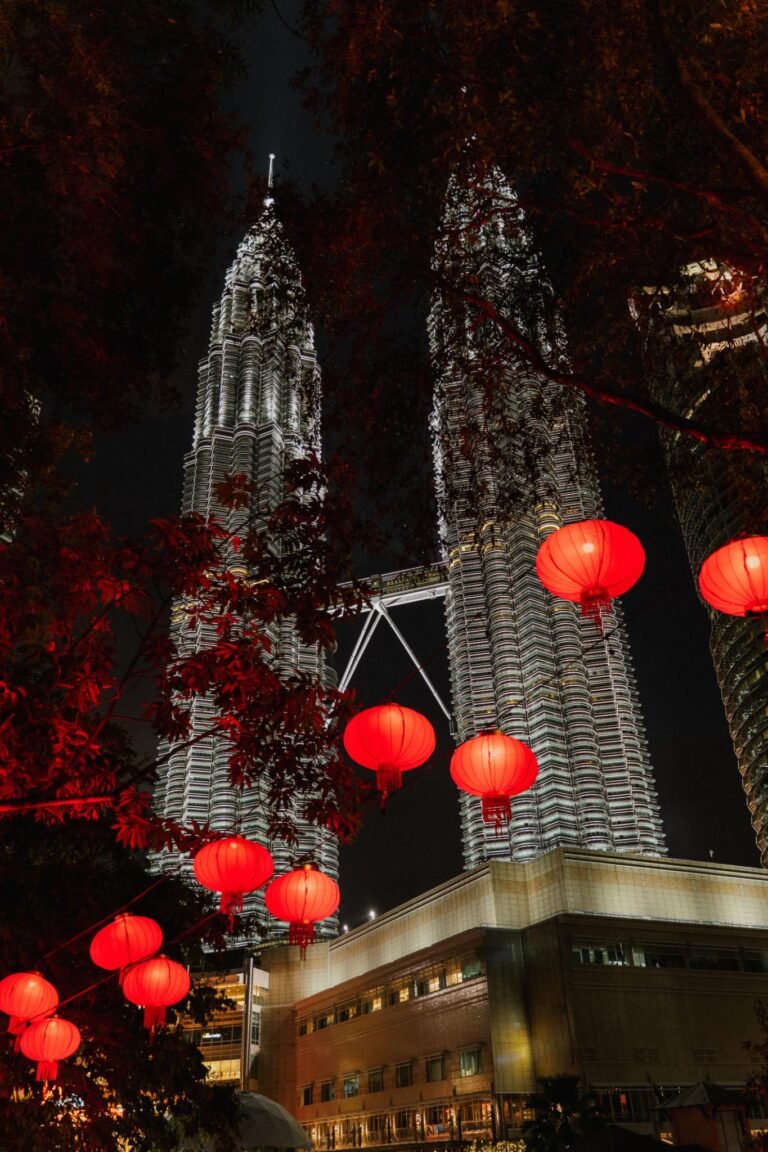 Petronas Twin Towers in Kuala Lumpur illuminated at night with red Chinese lanterns during Chinese New Year celebration in Malaysia.